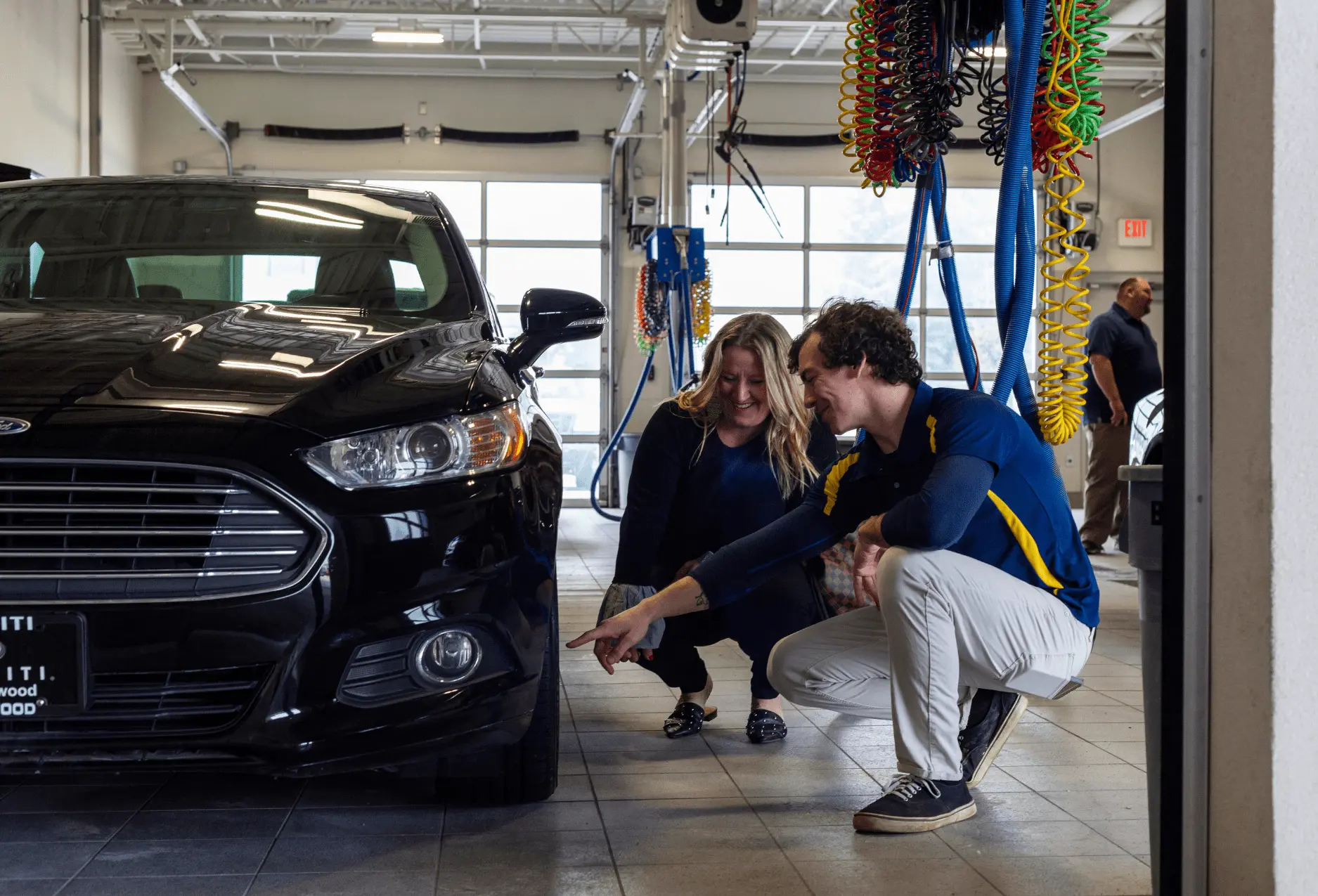 A Nathan's Detailing employee going over the exterior of a car with a client.